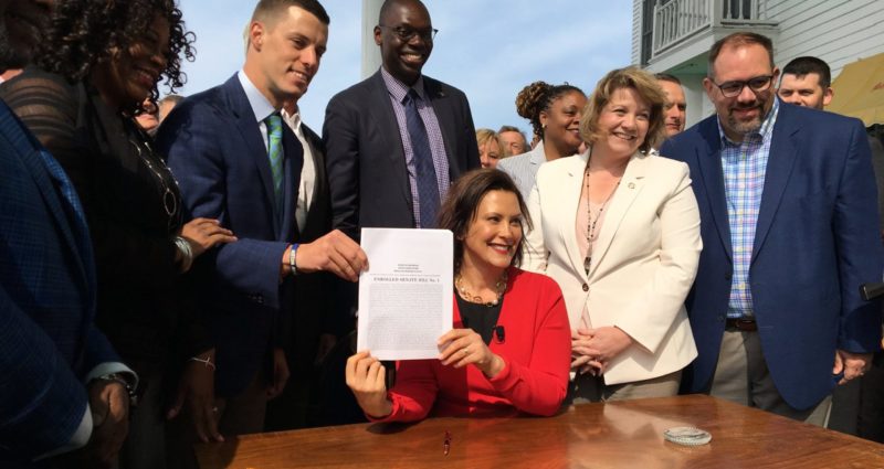 Michigan Gov. Gretchen Whitmer holds up a recently signed piece of no-fault insurance legislation