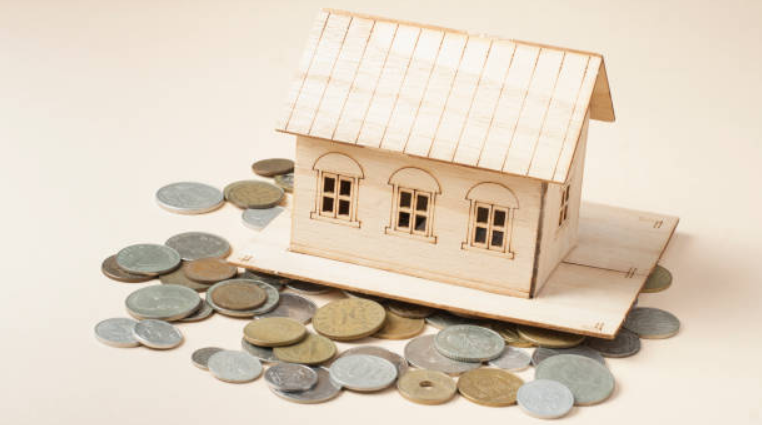 Coins scattered around a wooden model of a house.