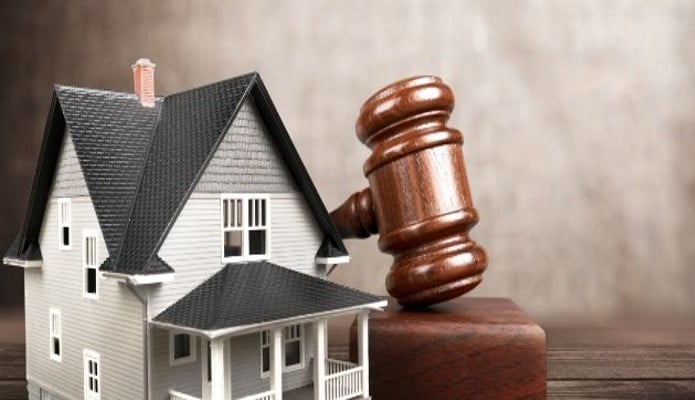 A courtroom gavel positioned next to a model home