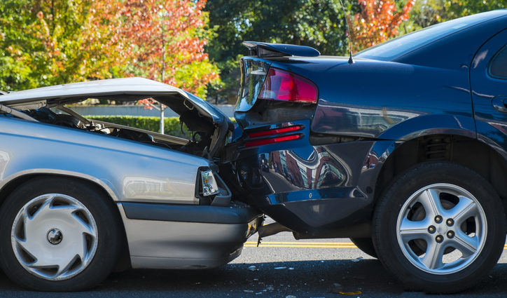 A grey sedan rear ends a black sports car in a crash causing significant damage.