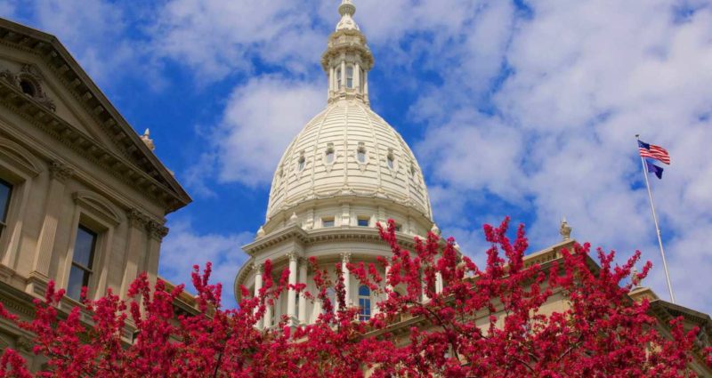 Red flowers frame the dome of the Michigan State Capitol Building