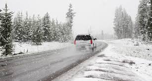 SUV driving around a curve during a winter snow storm.