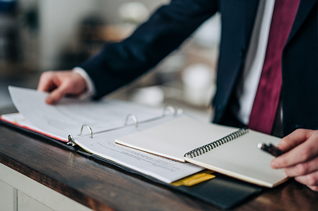 Man in a suit thumbing through documents and taking notes