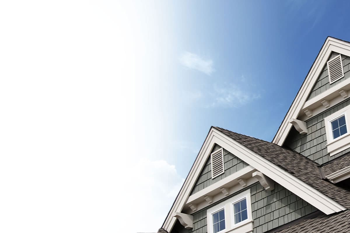 A photograph of a top of a house. A frame windows and big open shot of a blue sky.
