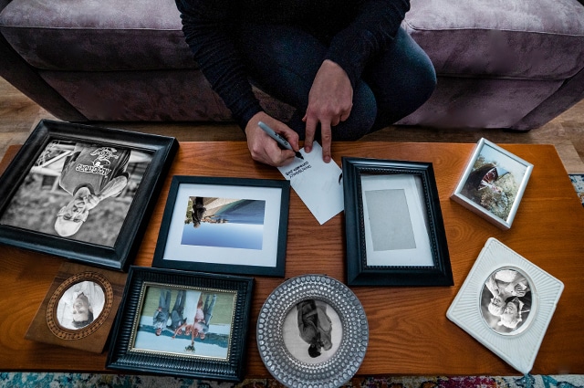Close up of woman writing with picture frames on a coffee table