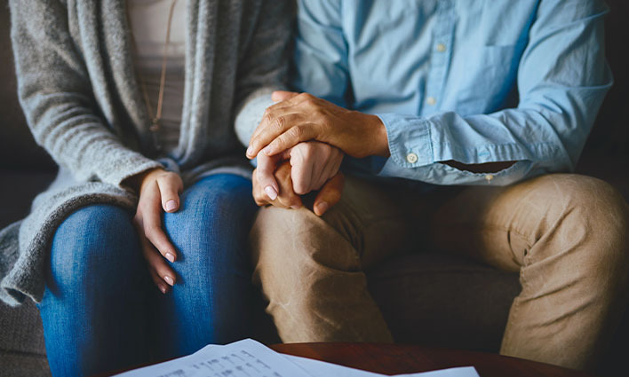 Couple holding hands to support one another during a lawsuit