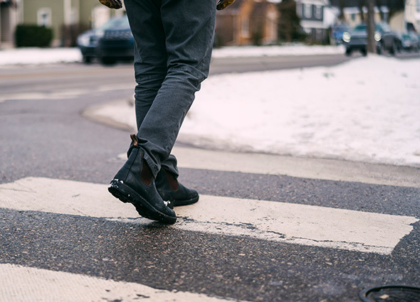 View of a Man's legs as he walks across a snowy crosswalk