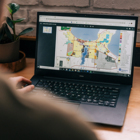 View over a man's shoulder showing a laptop with a city zoning map