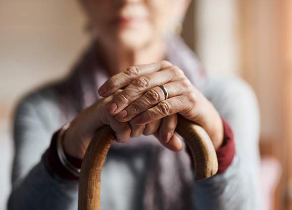 An extreme close up view of an elderly woman's hand on the top of a cane