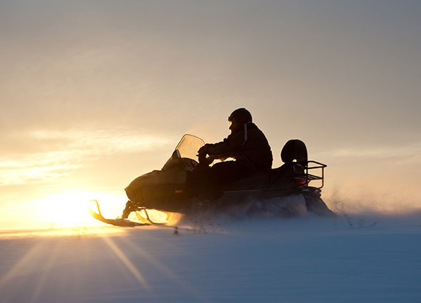 Silhouette of snowmobile rider with a sunset in the background